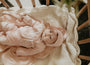 Baby in a pink outfit lying on a textured blanket