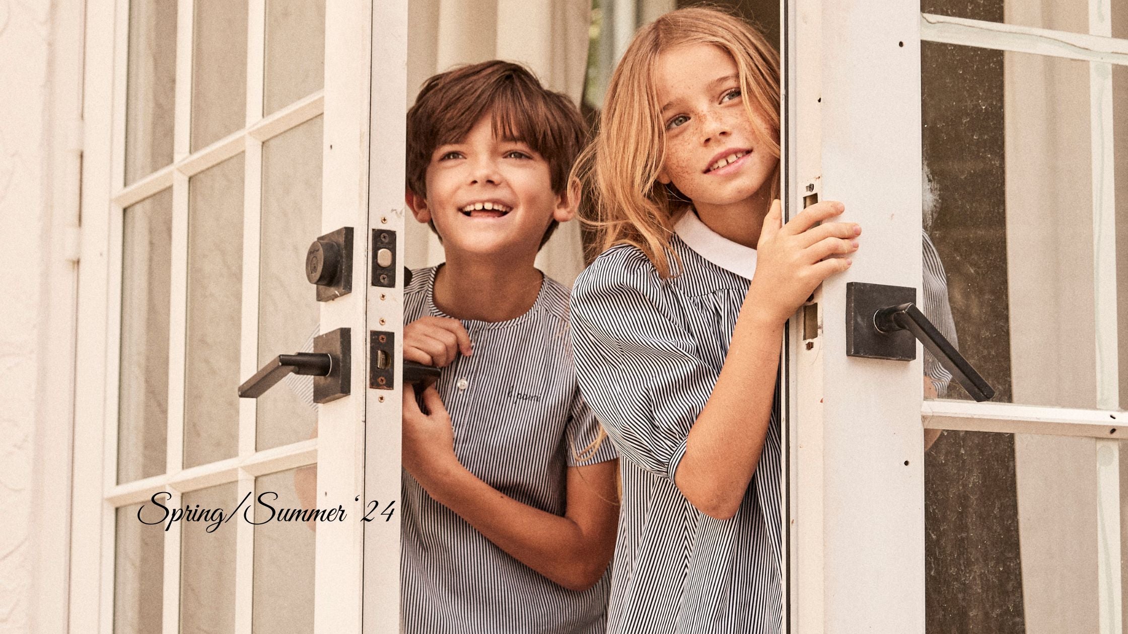 Little girl and boy dressed in elegant clothes opening a door and looking outside