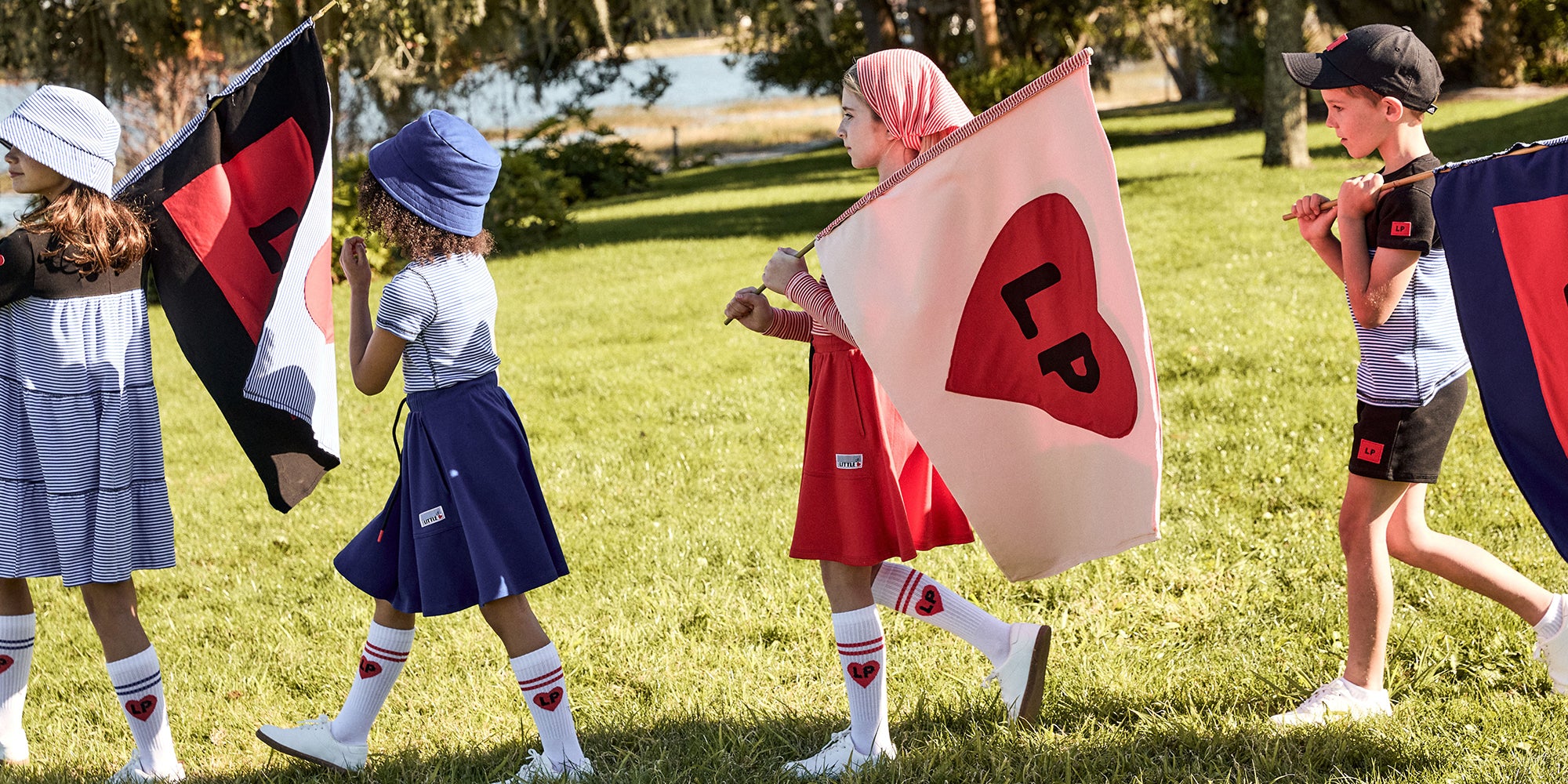 Children holding flags with symbols in a grassy outdoor setting